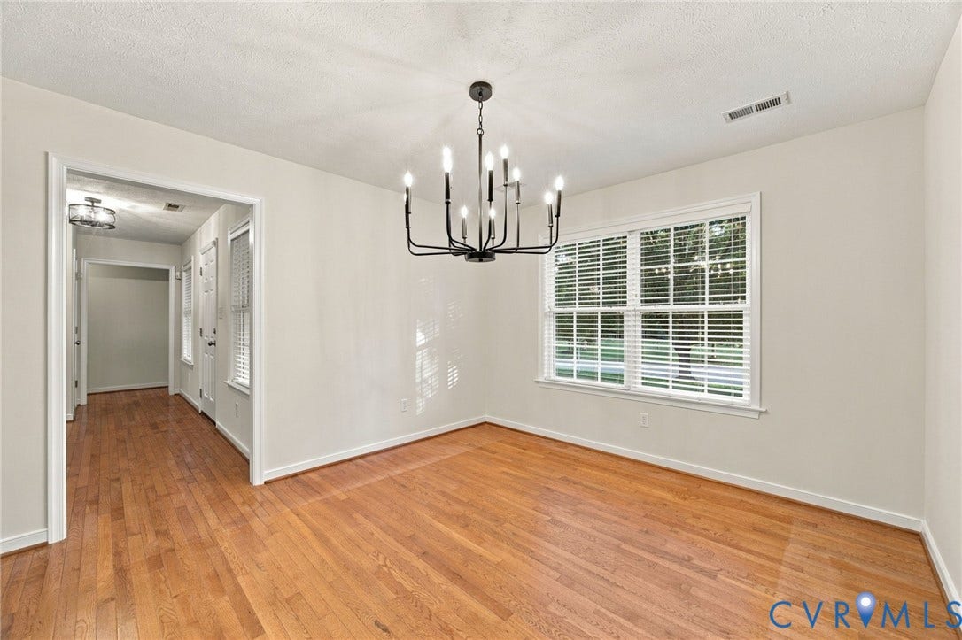 Dining area featuring wood-finish flooring, a multi-arm metal chandelier, and a wide window with horizontal blinds
