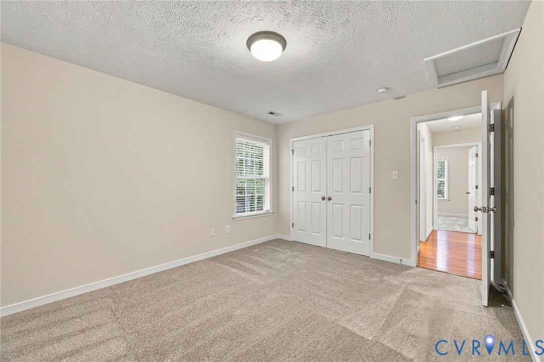 Room featuring neutral-toned carpeting, double-panel closet doors, a single window, and a ceiling-mounted light fixture