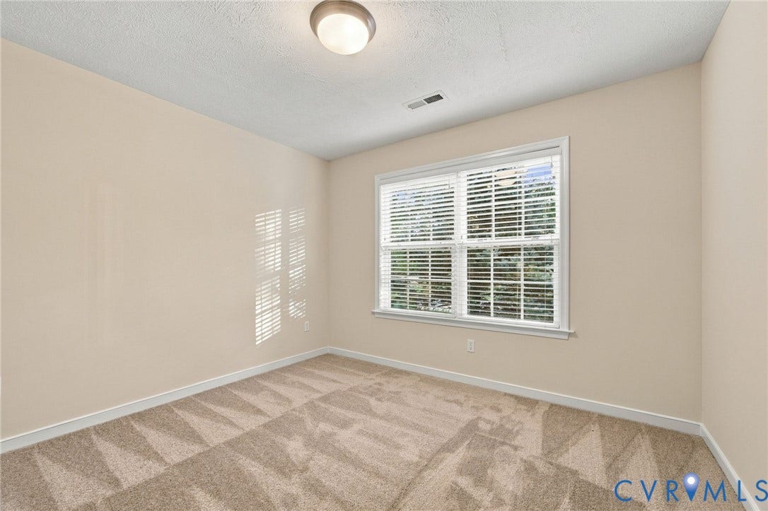 Neutral wall tones, wall-to-wall carpeting, large window with horizontal blinds, and flush-mount ceiling lighting