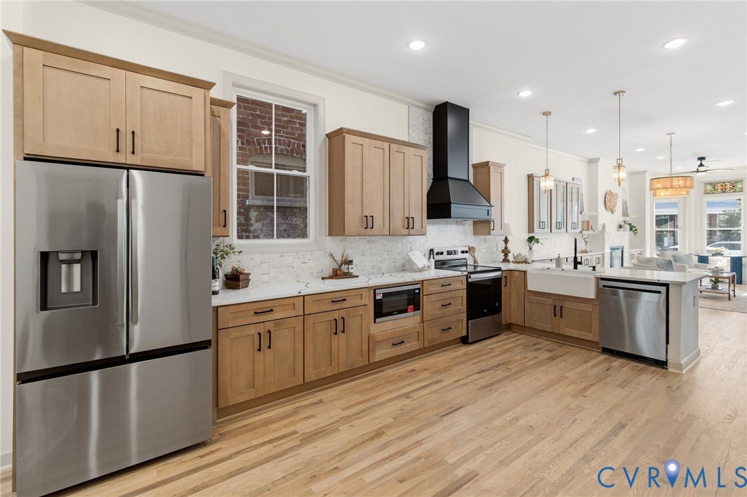 3104 E Broad Street, Richmond, VA 23223 Kitchen featuring light-tone wood cabinetry, stone countertops, farmhouse-style sink, stainless steel appliances, and a matte black range hood