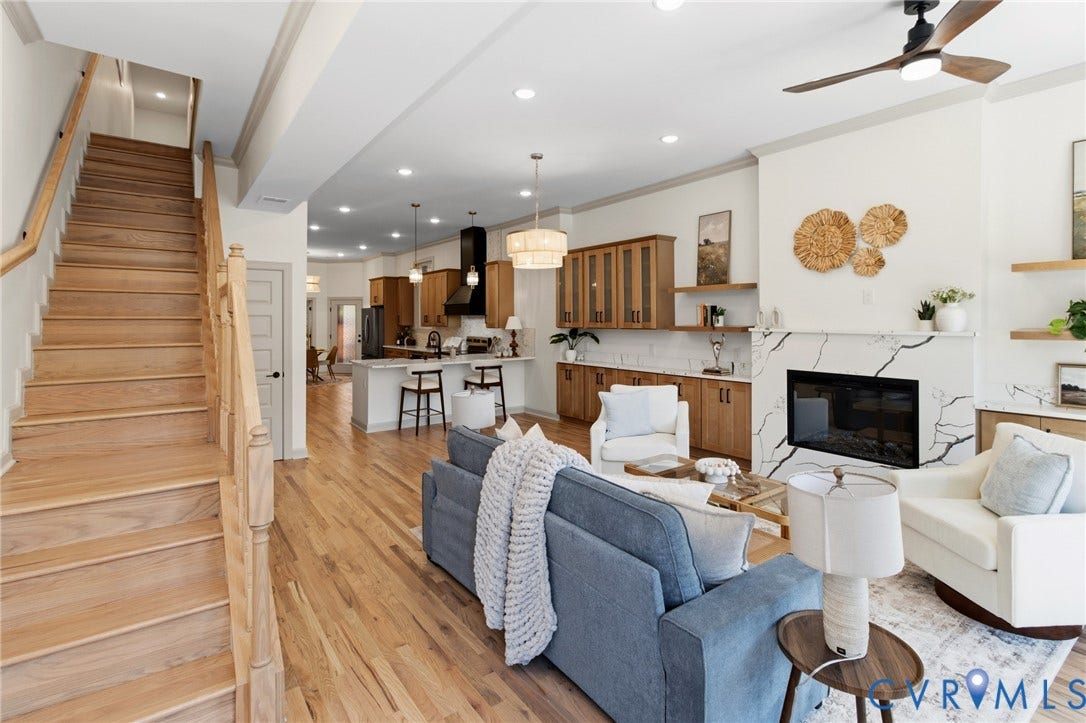3104 E Broad Street, Richmond, VA 23223 Open-concept interior featuring light wood-finish flooring, a fireplace with a stone-finish surround, custom built-in wood cabinetry, and an attached wooden staircase with a matching handrail