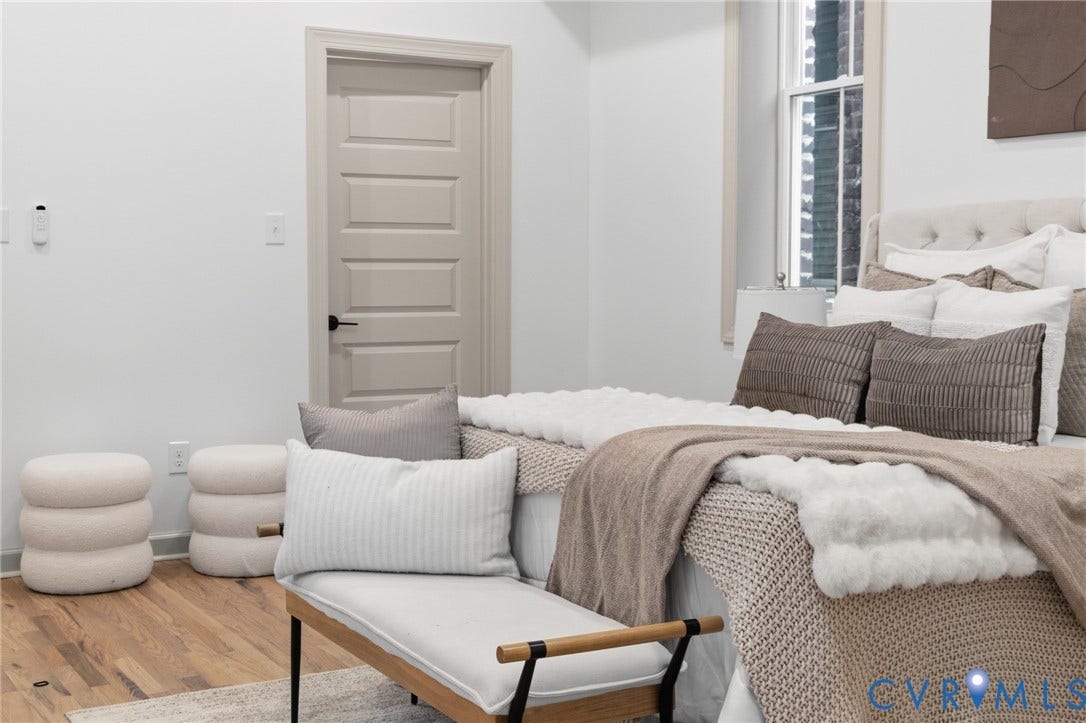 3104 E Broad Street, Richmond, VA 23223 Neutral interior featuring wood-finish flooring, a classic four-panel interior door with matte black hardware, and an energy-efficient window with clean trim