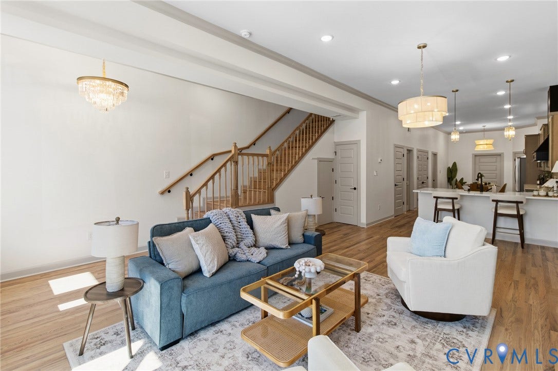 3104 E Broad Street, Richmond, VA 23223 Open floor plan featuring wood-finish flooring, recessed lighting, tiered crystal chandeliers, a wooden staircase with balustrades, and a kitchen island with stone countertop