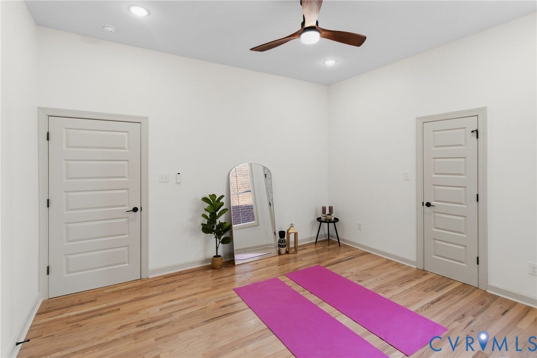 3104 E Broad Street, Richmond, VA 23223 High-ceiling room featuring light-toned wood-finish flooring, recessed lighting, a ceiling fan with integrated lighting, and two five-panel interior doors with matte black hardware