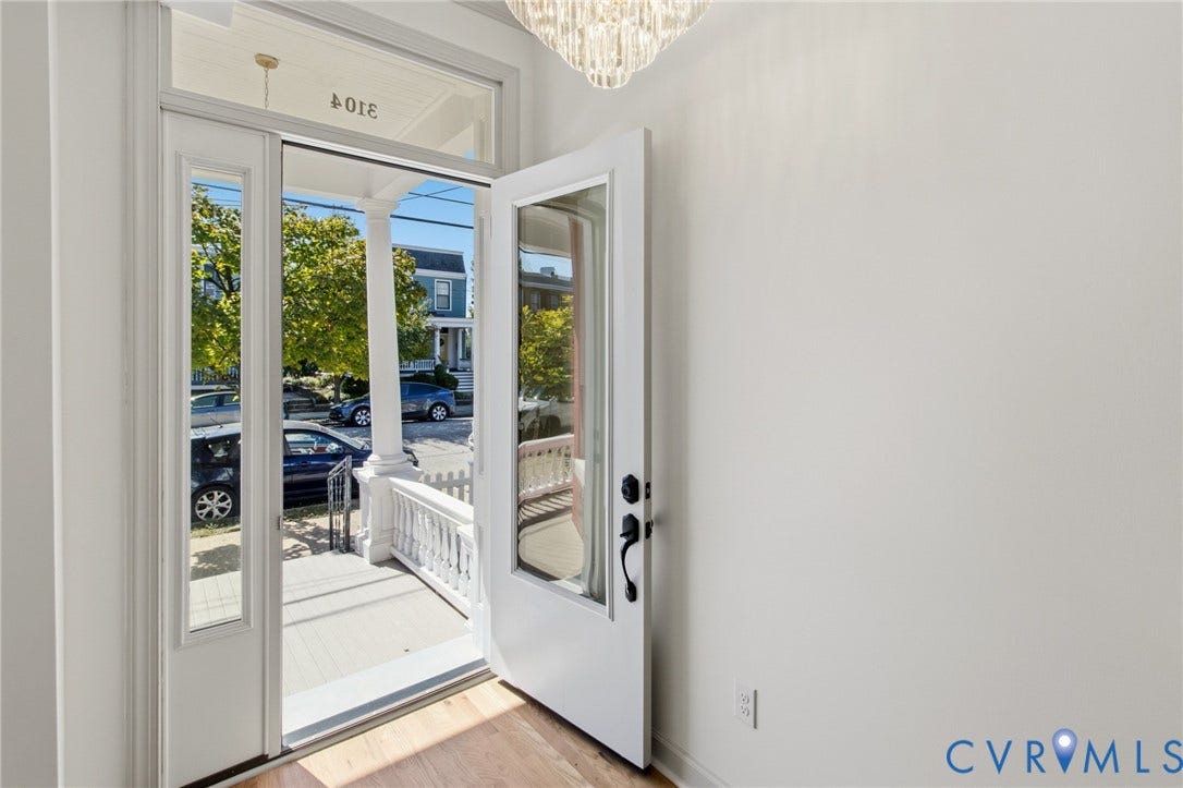 3104 E Broad Street, Richmond, VA 23223 Entryway featuring a glass-panel door with sidelight, overhead crystal-style chandelier, transom window, and light-tone wood-finish flooring
