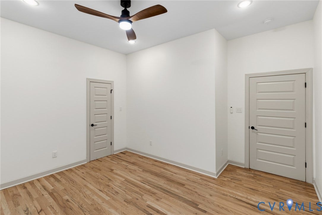 3104 E Broad Street, Richmond, VA 23223 Interior room featuring wood-finish flooring, a modern three-blade ceiling fan with integrated lighting, recessed ceiling lights, and two multi-panel doors with matte black hardware