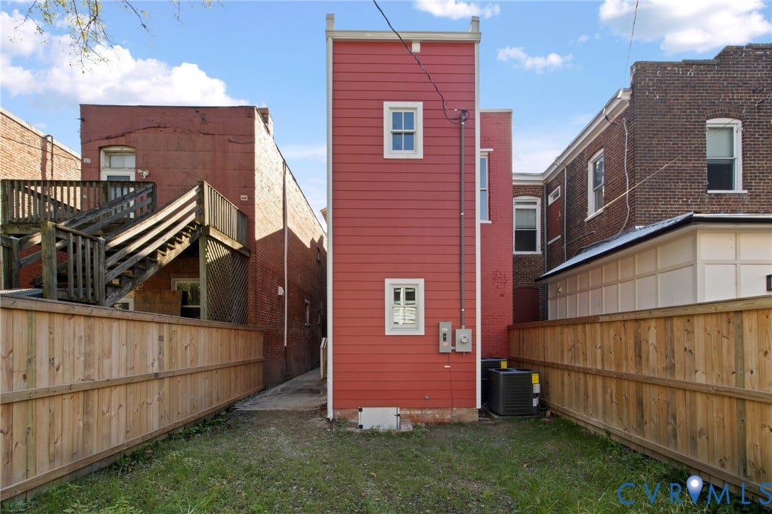 3104 E Broad Street, Richmond, VA 23223 Exterior view featuring horizontal siding, double-hung windows, and a wood-paneled privacy fence enclosing the yard area