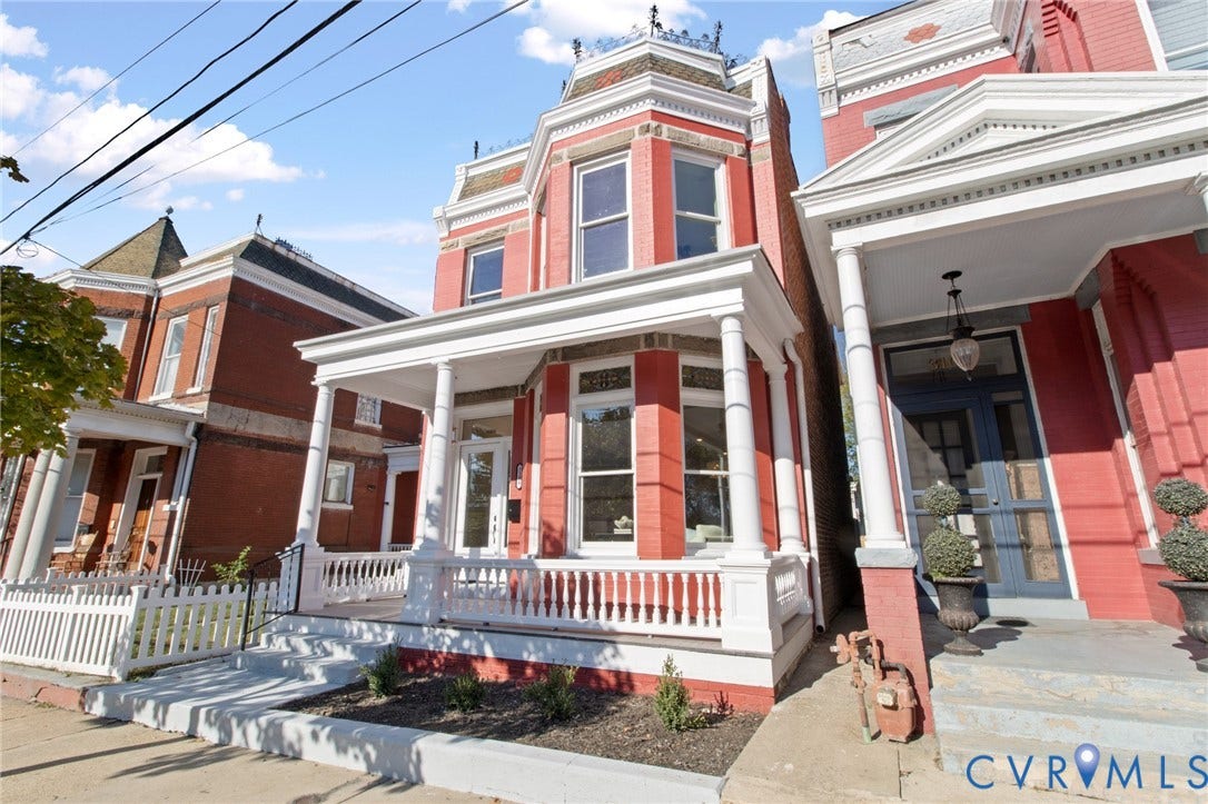 3104 E Broad Street, Richmond, VA 23223 Red brick facade featuring a covered front porch, white railings, decorative cornice detailing, and multi-pane windows