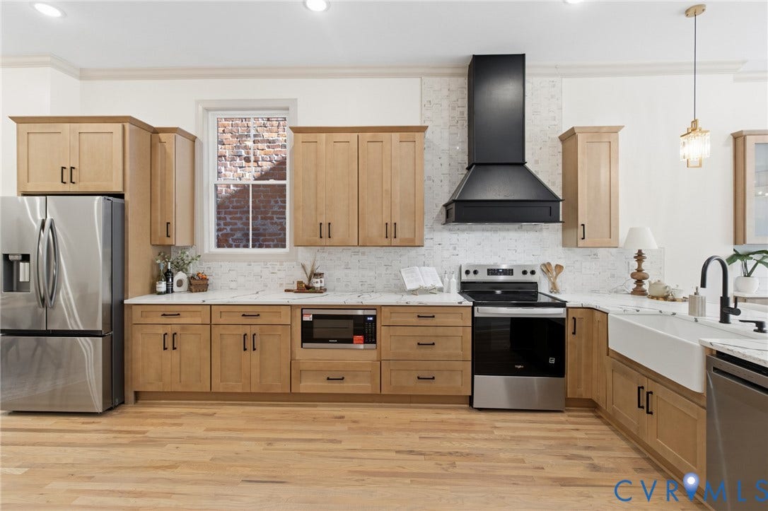3104 E Broad Street, Richmond, VA 23223 Kitchen featuring light wood-finish cabinetry, stone-surface countertops, a porcelain farmhouse sink, a matte black range hood, and wood-finish flooring