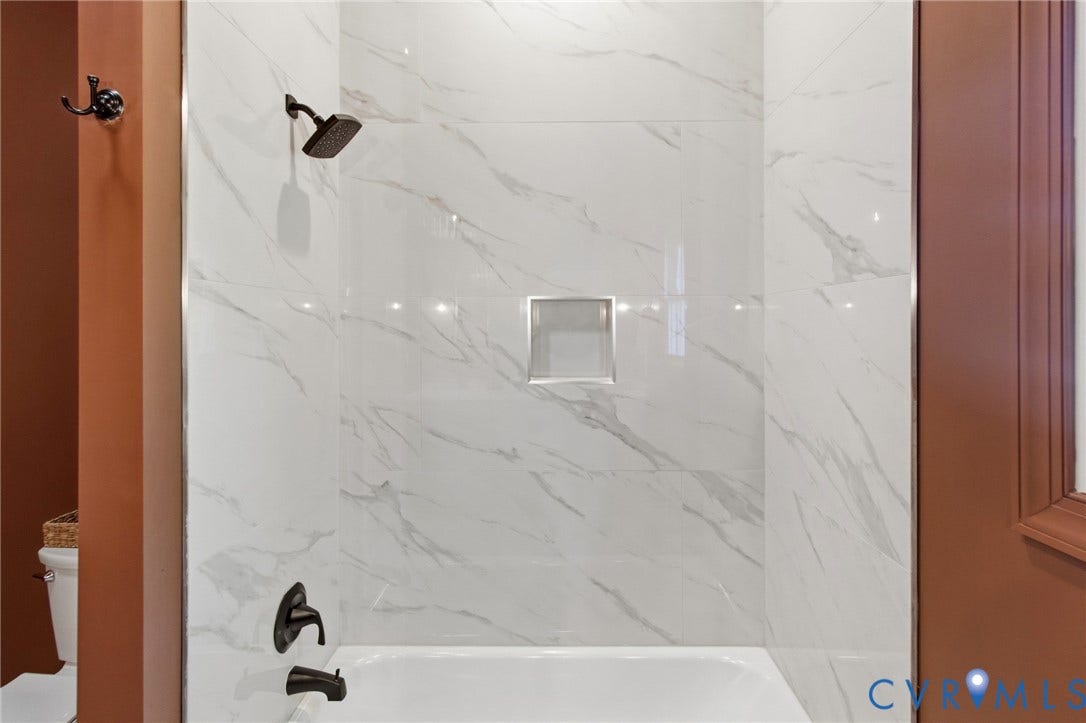 3104 E Broad Street, Richmond, VA 23223 Shower enclosure featuring large-format veined tile surround, recessed wall niche, and matte black plumbing fixtures