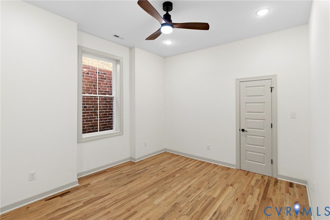 3104 E Broad Street, Richmond, VA 23223 Room featuring wood-finish flooring, recessed lighting, a ceiling fan with integrated lighting, a single-hung window with a brick exterior reveal, and a five-panel interior door