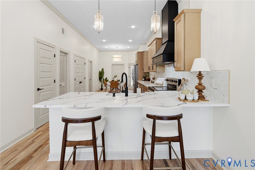 3104 E Broad Street, Richmond, VA 23223 Kitchen featuring stone-finish countertops with veining, light wood-finish cabinetry, a matte black range hood, wood-finish flooring, and pendant lighting