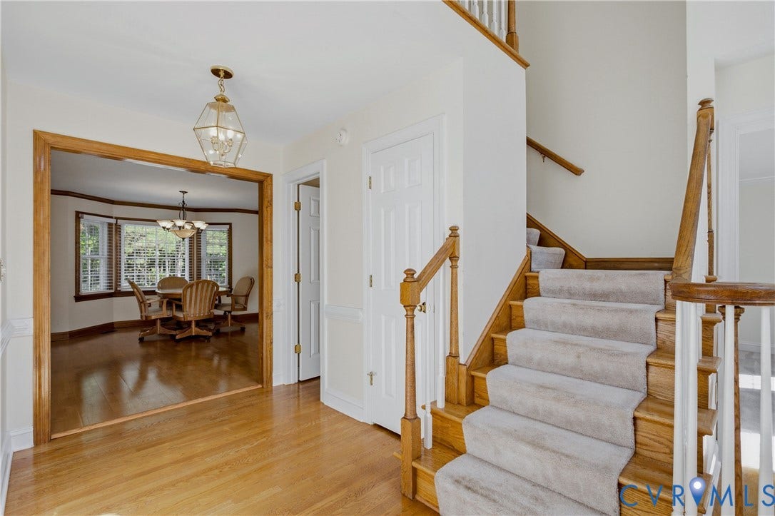 11400 County Drive, Prince George, VA 23842 Foyer featuring wood-finish flooring, staircase with wood handrail, paneled interior door, and a pendant light fixture