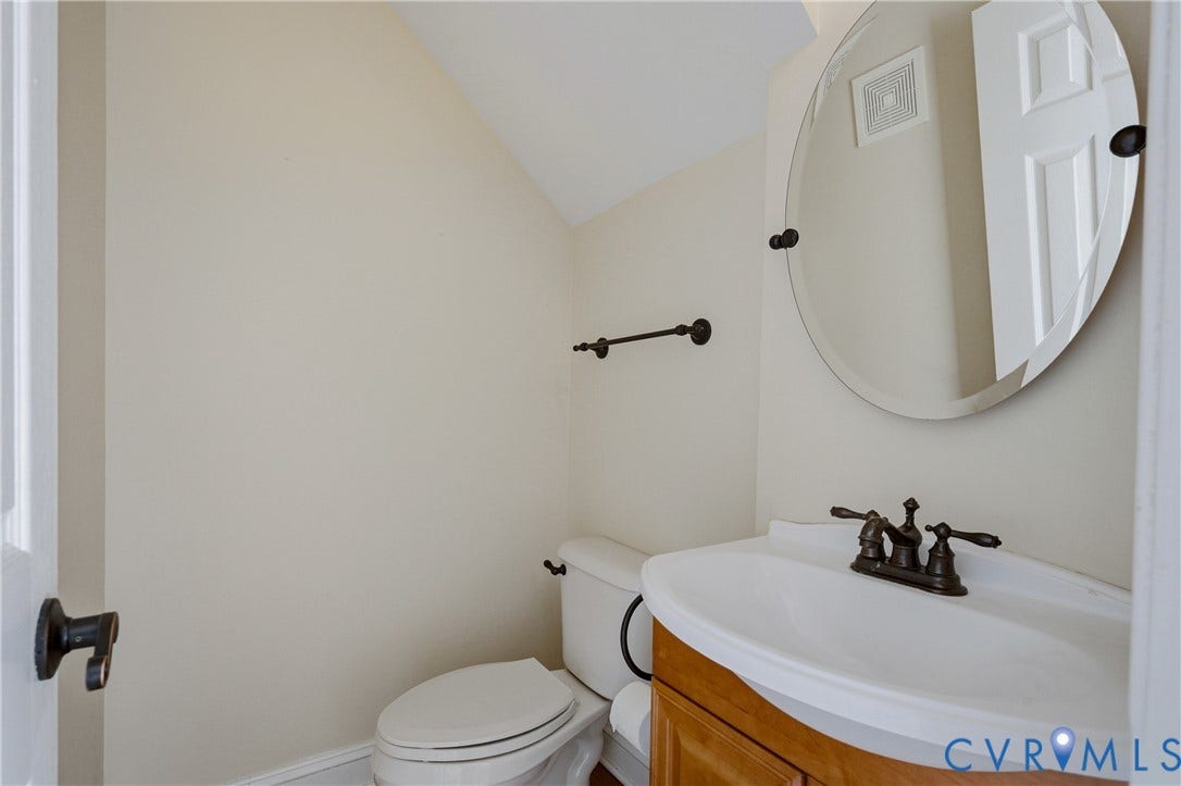 11400 County Drive, Prince George, VA 23842 Wall-mounted oval mirror, wood-finish vanity cabinet, white porcelain sink