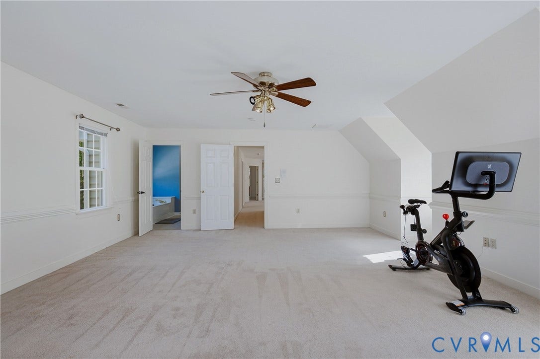 11400 County Drive, Prince George, VA 23842 Spacious room featuring neutral carpeting, sloped ceiling architecture, chair rail molding, and a central ceiling fan with integrated lighting