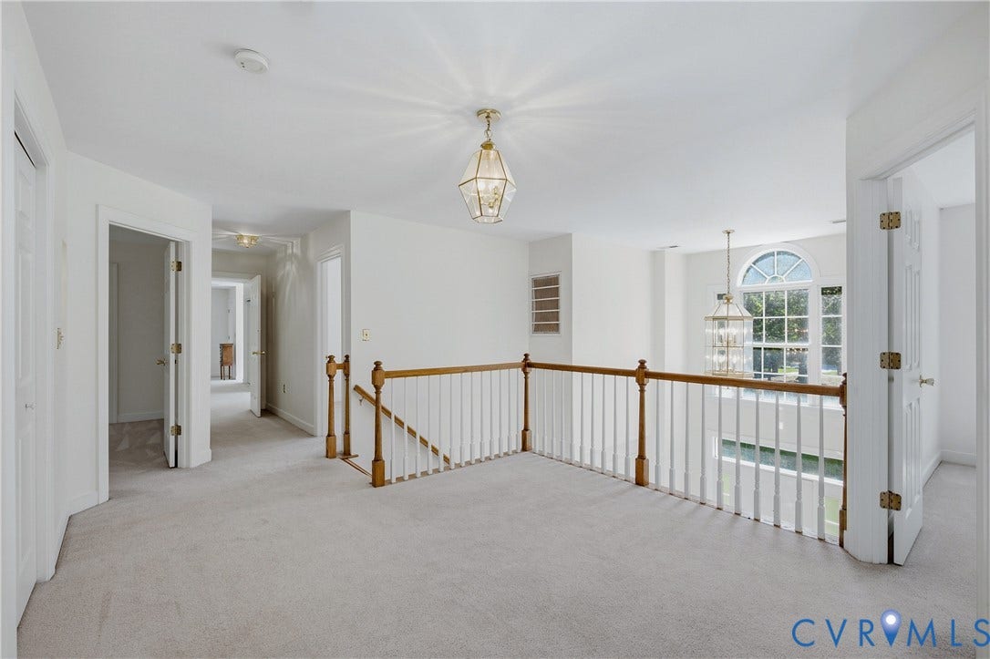 11400 County Drive, Prince George, VA 23842 Open landing area featuring wood-finish handrails, white balusters, multi-pane arched window, and two tiered metal-frame pendant light fixtures