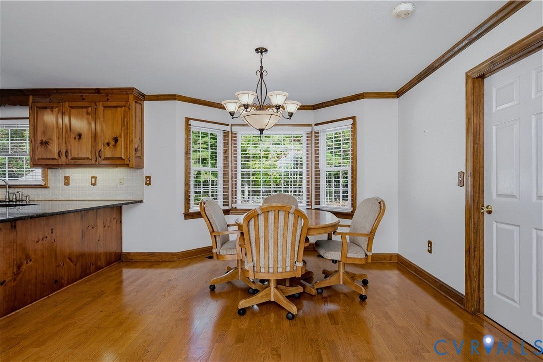11400 County Drive, Prince George, VA 23842 Bay window featuring wood-trimmed casing, natural wood-finish flooring, custom wood cabinetry, and a chandelier