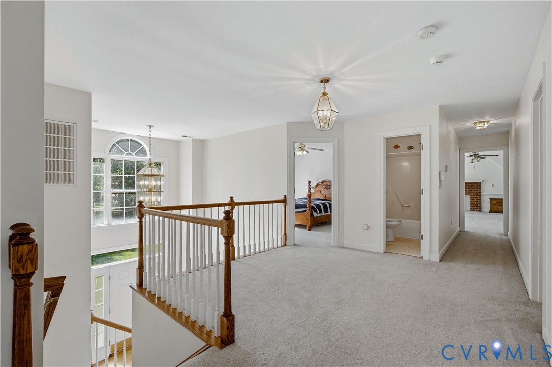 11400 County Drive, Prince George, VA 23842 Open-concept landing featuring wall-to-wall carpeting, wood-finish balustrade with white spindles, decorative pendant lighting, and an arched transom window