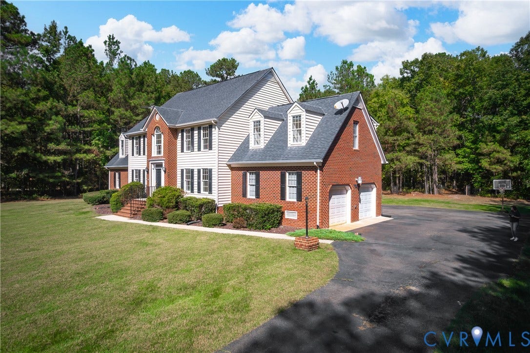 11400 County Drive, Prince George, VA 23842 Two-story traditional exterior featuring a brick and vinyl-sided facade, multiple roof dormers, a multi-car attached garage, and an expansive lawn