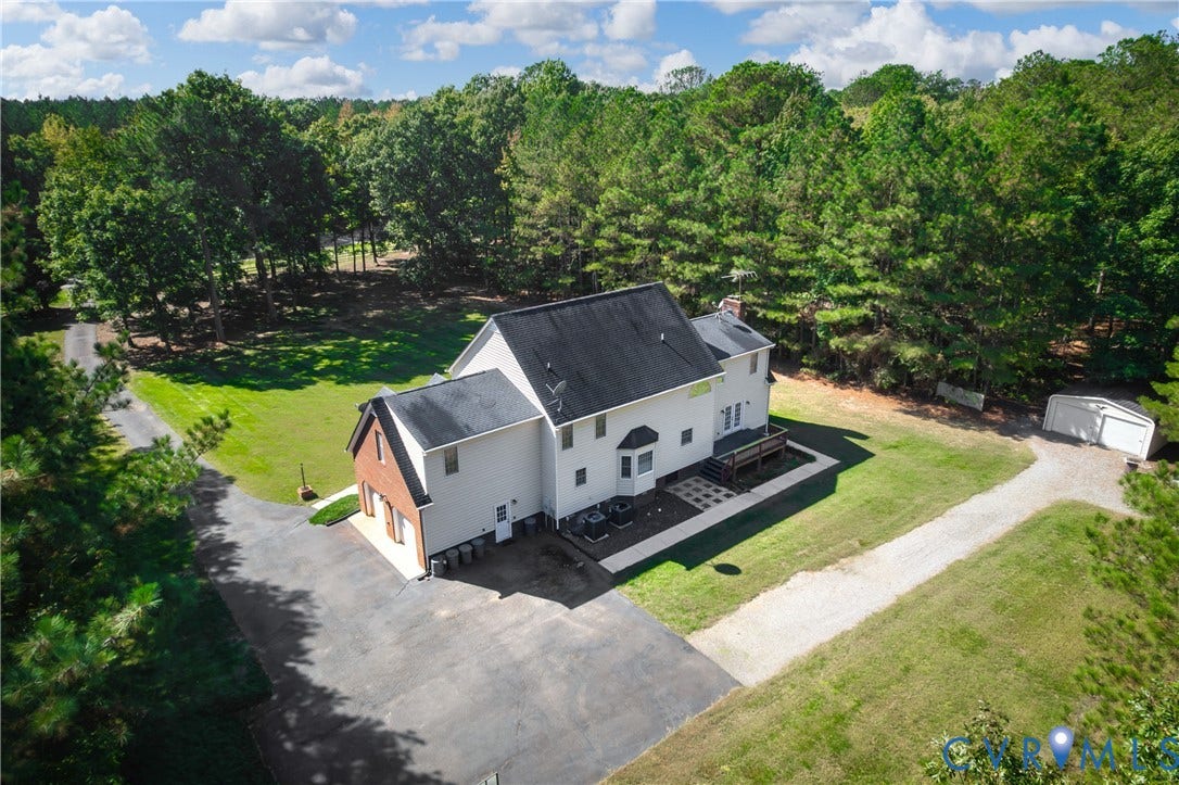 11400 County Drive, Prince George, VA 23842 Aerial perspective of a multi-story residence featuring a brick and siding exterior, an attached garage, a paved driveway, and a detached outbuilding on a wooded lot