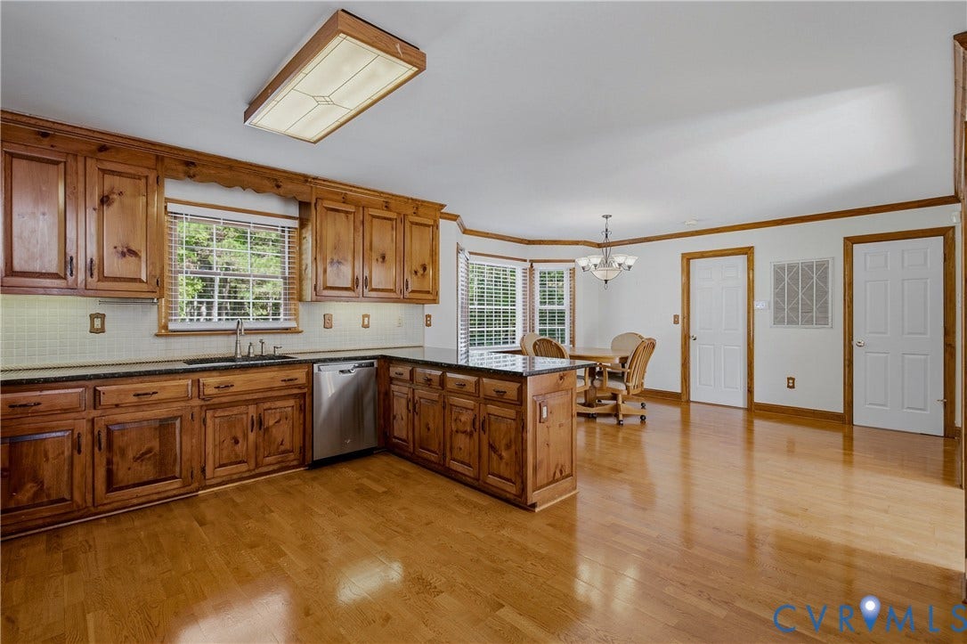 11400 County Drive, Prince George, VA 23842 Kitchen featuring solid wood cabinetry, dark countertops, wood-finish flooring, a stainless steel dishwasher, and a bay window