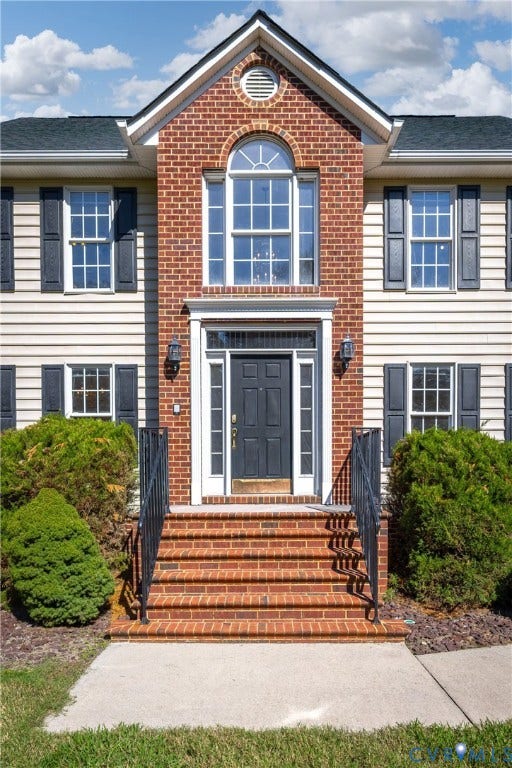 11400 County Drive, Prince George, VA 23842 Two-story exterior featuring a brick facade with horizontal siding, an arched window, a paneled front door with sidelights, and tiered brick steps with metal railings