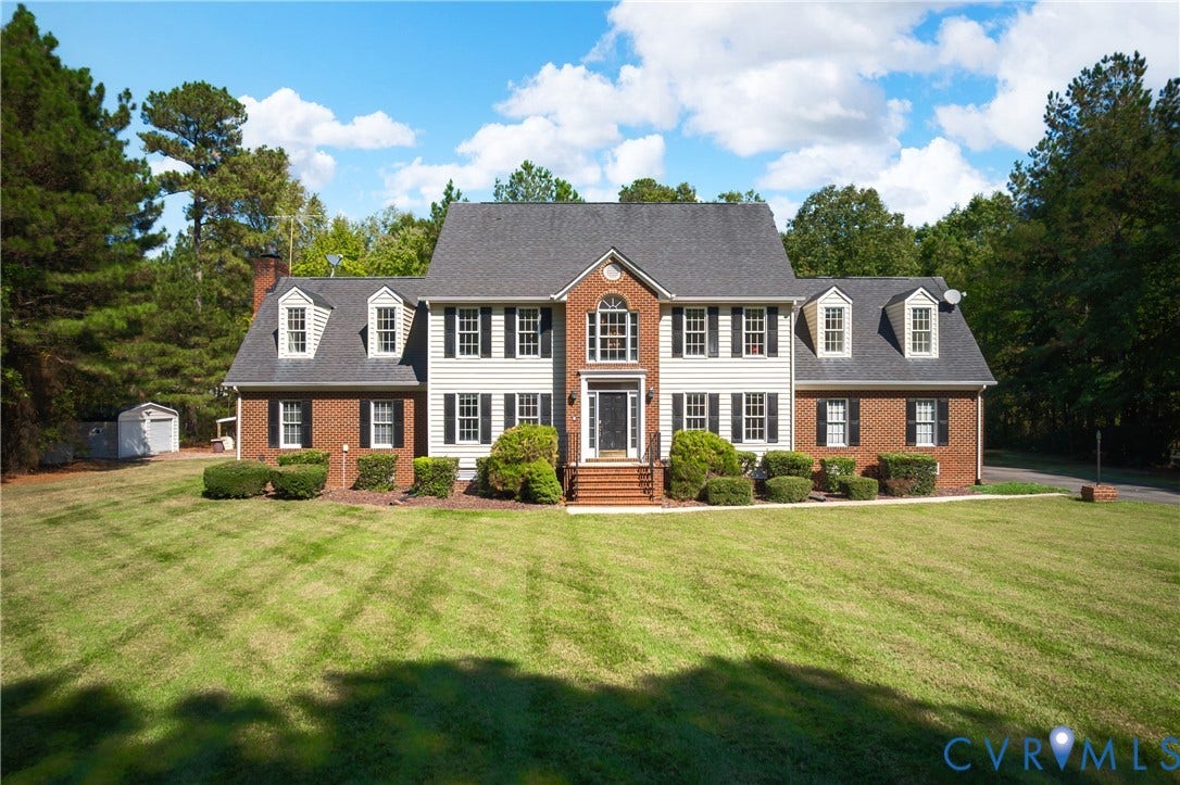 11400 County Drive, Prince George, VA 23842 Traditional two-story exterior featuring a brick and siding facade, multiple dormer windows, an arched entryway, and a shingled roof, set on a sprawling lot with mature trees