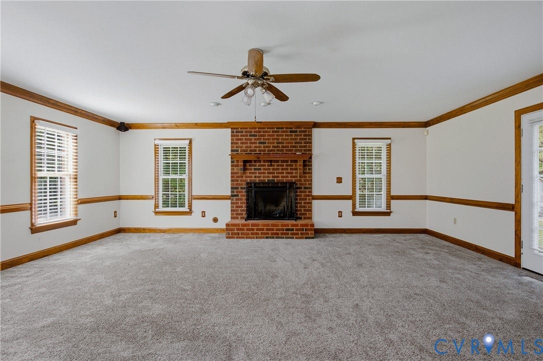 11400 County Drive, Prince George, VA 23842 Living area featuring a central brick fireplace with a wood mantel, multi-pane windows, wood-finish chair rail molding, and a ceiling fan
