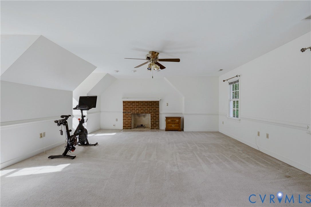 11400 County Drive, Prince George, VA 23842 Open-concept room featuring vaulted ceilings, a brick fireplace, wall-to-wall carpeting, a ceiling fan with integrated lighting, and a window with trim