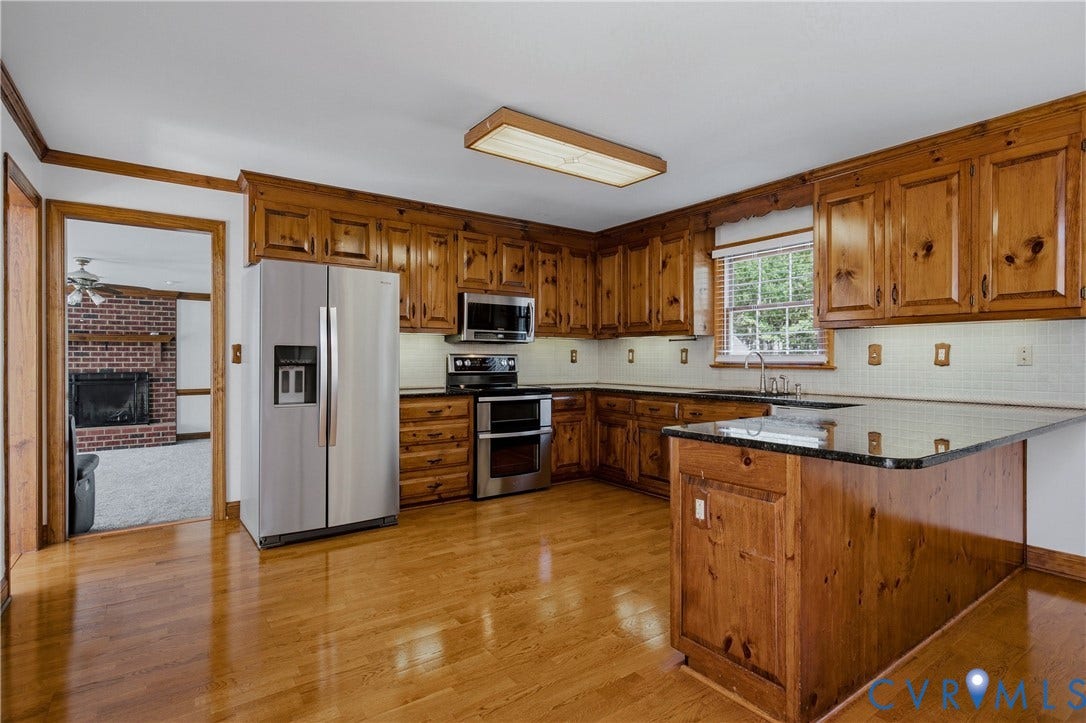 11400 County Drive, Prince George, VA 23842 Kitchen featuring custom stained-wood cabinetry, dark-finish countertops, stainless steel appliances, and wood-finish flooring