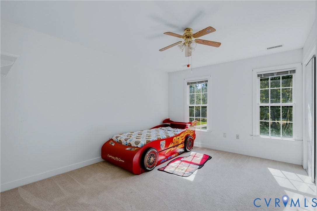 11400 County Drive, Prince George, VA 23842 Neutral-toned wall-to-wall carpeting, dual double-hung windows with exterior trim, and a ceiling-mounted fan with integrated light fixture