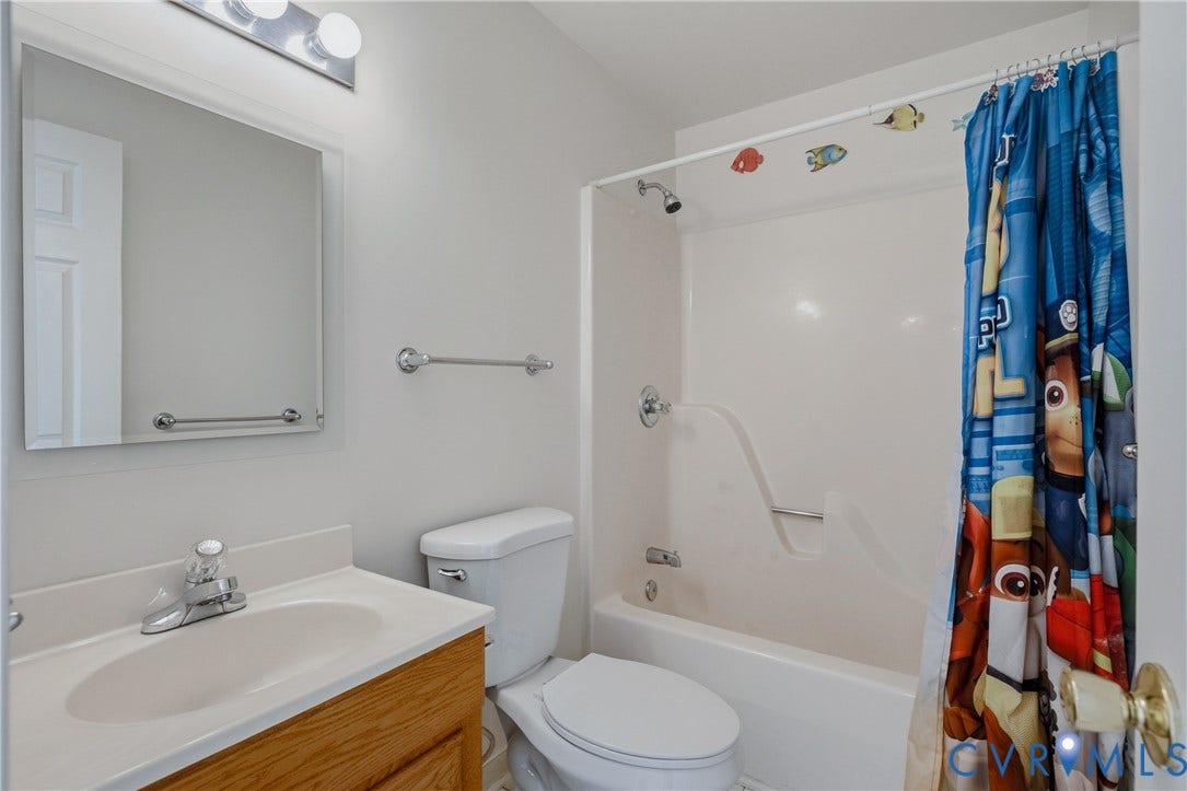 11400 County Drive, Prince George, VA 23842 Guest Bathroom featuring a wood-finish vanity with a molded countertop and integrated sink, a rectangular mirror, a polished chrome vanity light, and a white acrylic tub-shower combination