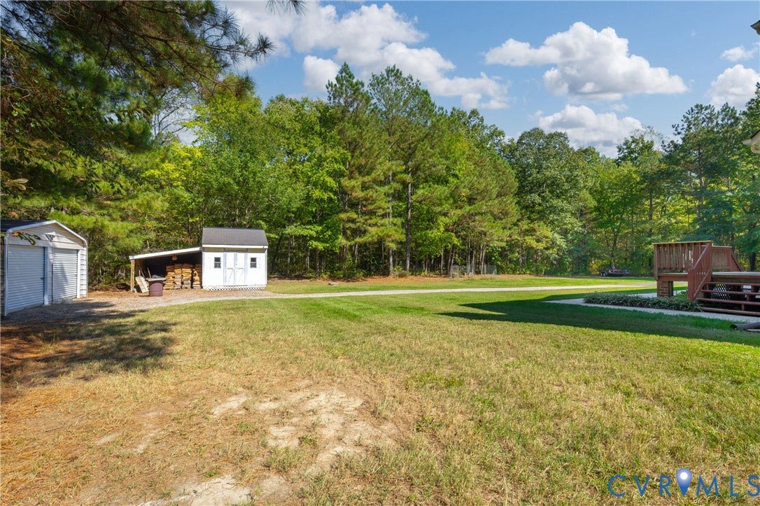 11400 County Drive, Prince George, VA 23842 Expansive rear grounds featuring a wood deck, detached garage, storage shed with an attached lean-to, and mature perimeter trees