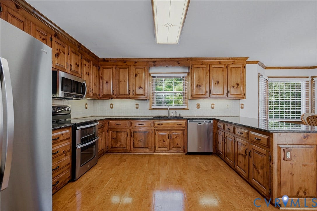 11400 County Drive, Prince George, VA 23842 Kitchen featuring wood cabinetry, countertops, stainless steel appliances, wood-finish flooring, and natural light via windows