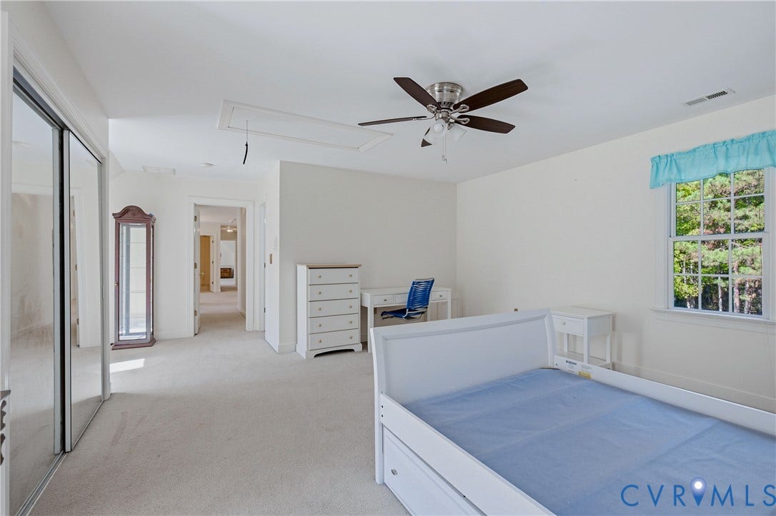 11400 County Drive, Prince George, VA 23842 Carpeted interior room featuring a ceiling fan with integrated lighting, sliding mirrored closet doors, and multi-pane windows