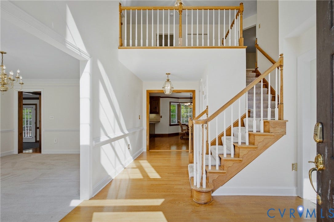 11400 County Drive, Prince George, VA 23842 Two-story foyer featuring wood-finish flooring, a staircase with a wooden handrail and white balusters, a second-story landing, and a hanging pendant light
