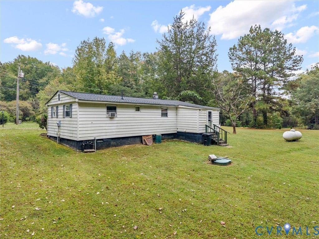 8631 Kimages Road, Charles City, VA 23030 Single-story exterior featuring light-colored horizontal siding, a pitched roof, and an expansive surrounding yard with mature trees