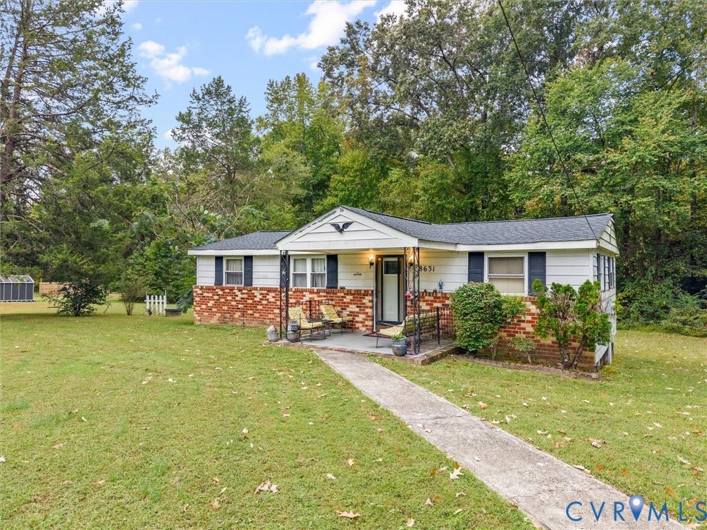 8631 Kimages Road, Charles City, VA 23030 Exterior featuring a brick and horizontal siding faade, covered front porch with iron support columns, and expansive grounds surrounded by mature trees