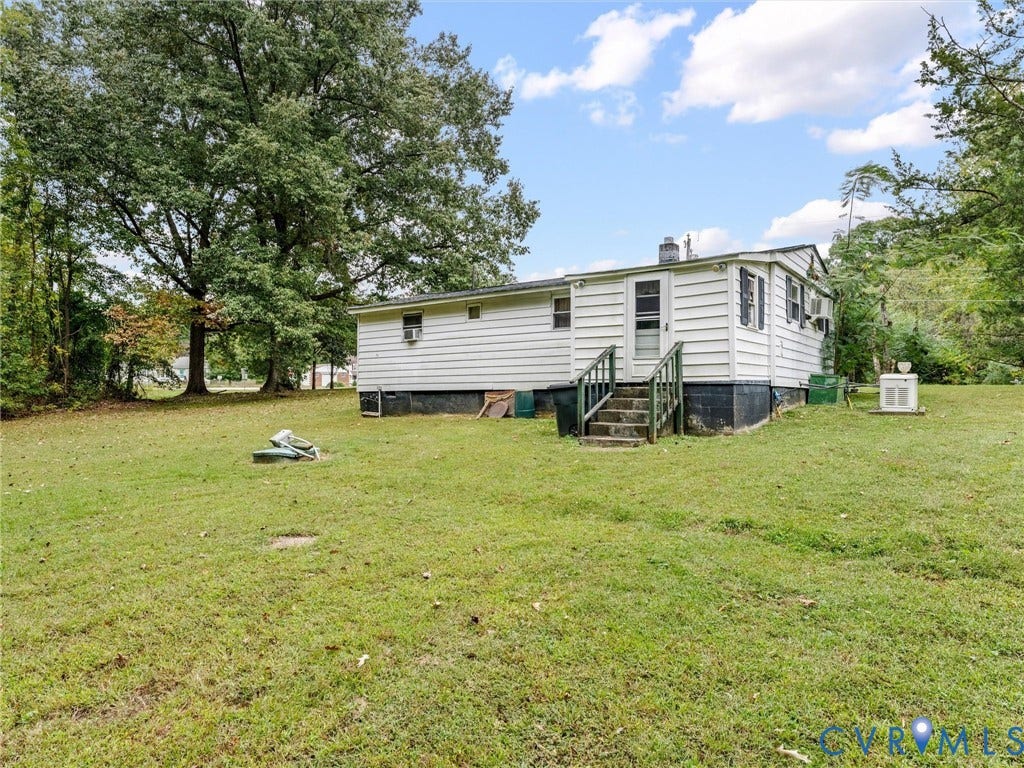 8631 Kimages Road, Charles City, VA 23030 Single-story exterior featuring white horizontal siding, dark-toned foundation, wood-frame steps, and mature tree-lined grounds