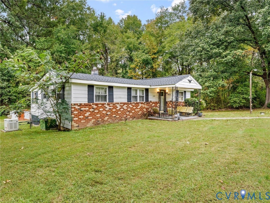 8631 Kimages Road, Charles City, VA 23030 Ranch-style exterior featuring a brick and white siding facade, asphalt shingle roof, covered front porch with iron supports, and a large lot with mature trees