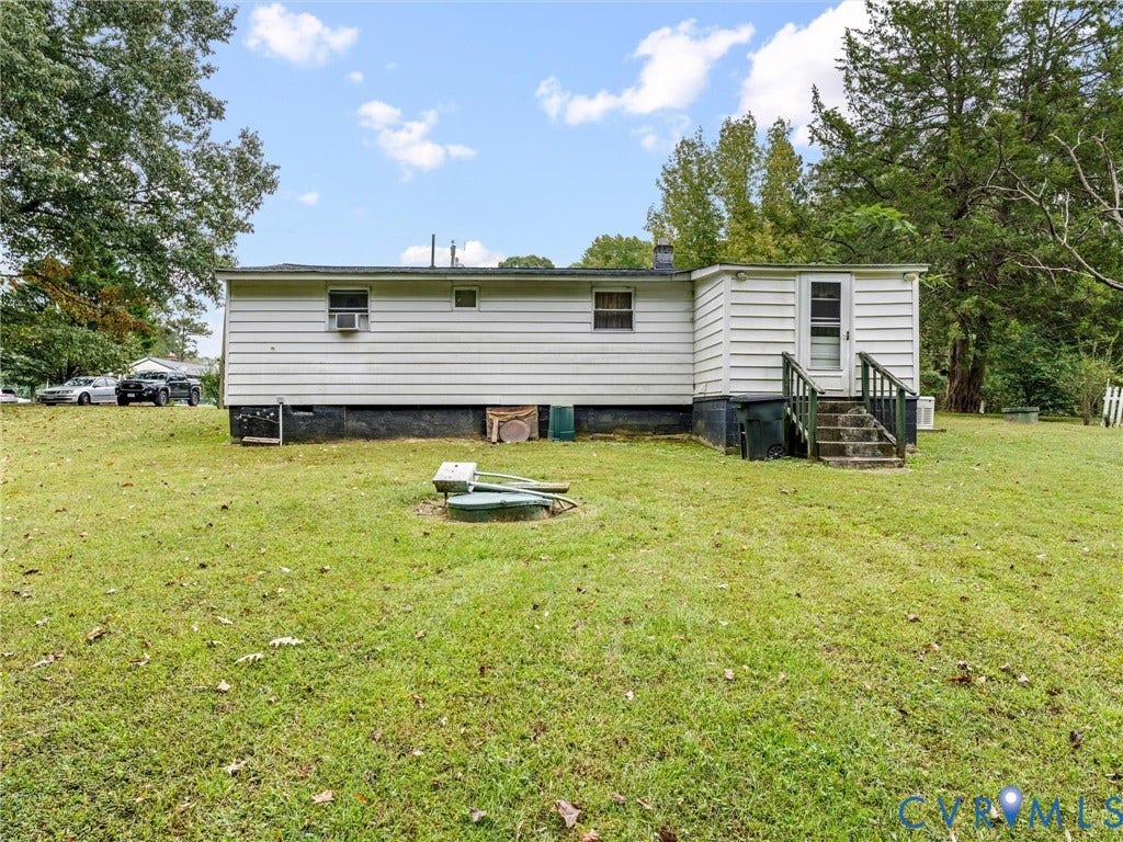 8631 Kimages Road, Charles City, VA 23030 Exterior rear elevation featuring horizontal siding, a concrete staircase with railings, and expansive green space with mature trees
