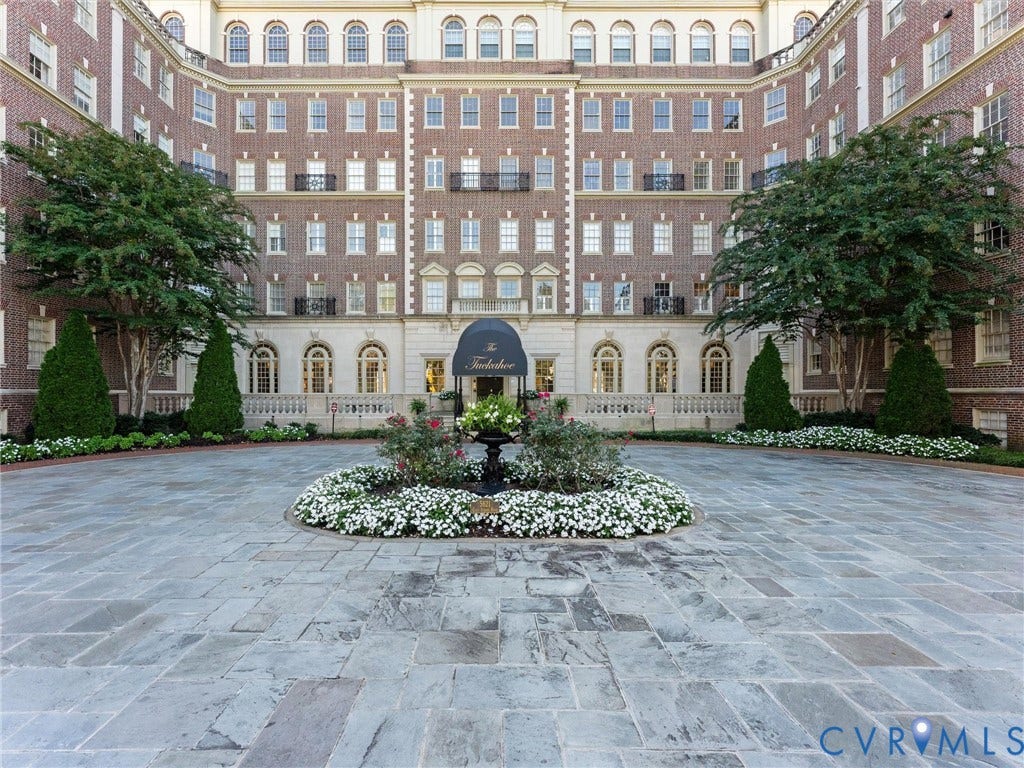5621 Cary Street Road, #U506, Richmond, VA 23226 Brick exterior facade featuring a symmetrical architectural design, arched window detailing, stone balustrade, central portico entrance, and a paved stone motor court