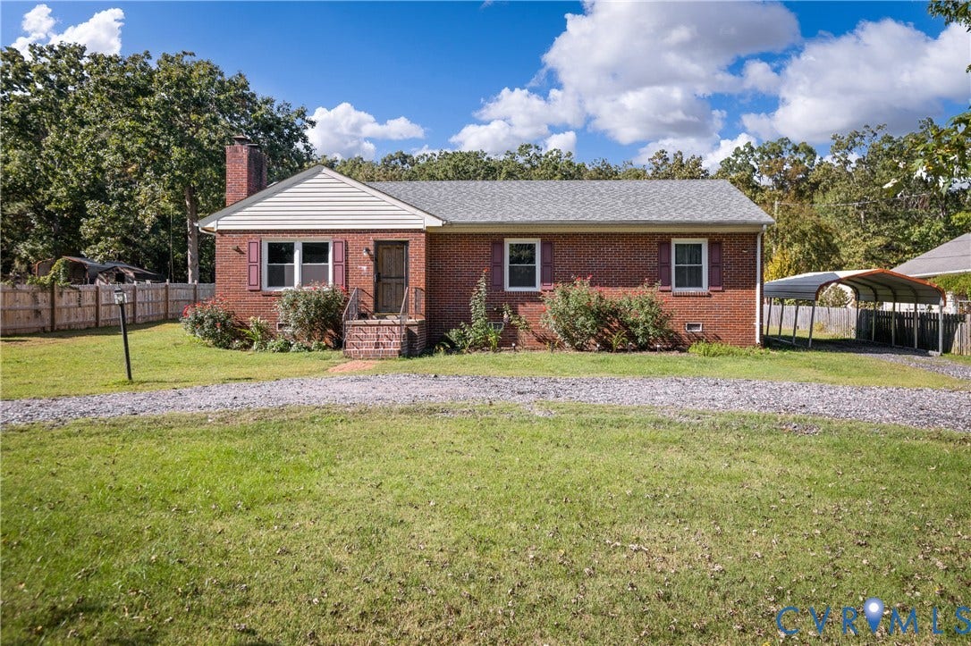 9834 N Wagstaff Circle, Mechanicsville, VA 23236 Brick exterior residence featuring a gable roof, exterior chimney, covered carport, and a gravel driveway