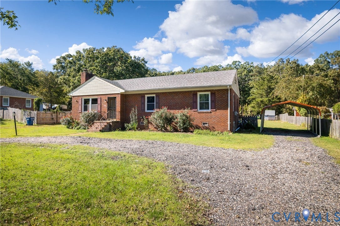 9834 N Wagstaff Circle, Mechanicsville, VA 23236 Brick exterior residence featuring a gabled roofline, decorative window shutters, a gravel driveway, and a detached metal carport