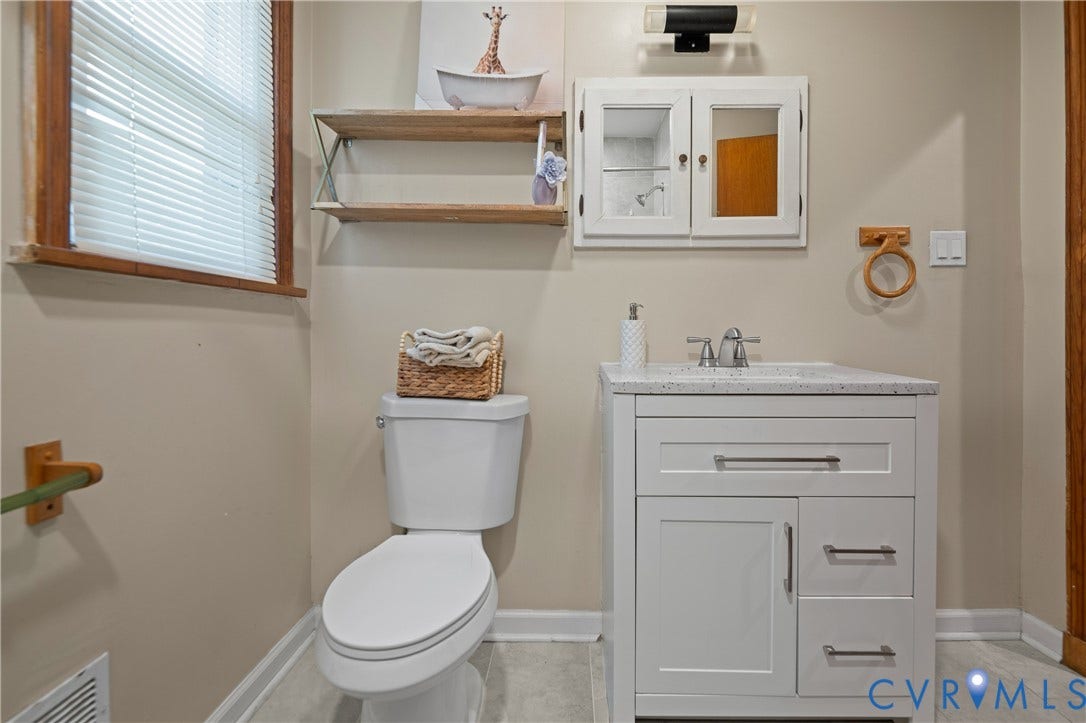 9834 N Wagstaff Circle, Mechanicsville, VA 23236 White vanity with stone-composite countertop, dual-handle faucet, surface-mount medicine cabinet, wall-mounted shelving, and tile flooring