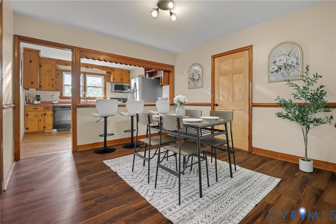 9834 N Wagstaff Circle, Mechanicsville, VA 23236 Dining area featuring wood-finish flooring, a decorative scalloped pass-through opening, natural wood trim, a six-panel solid wood door, and three-light track fixture