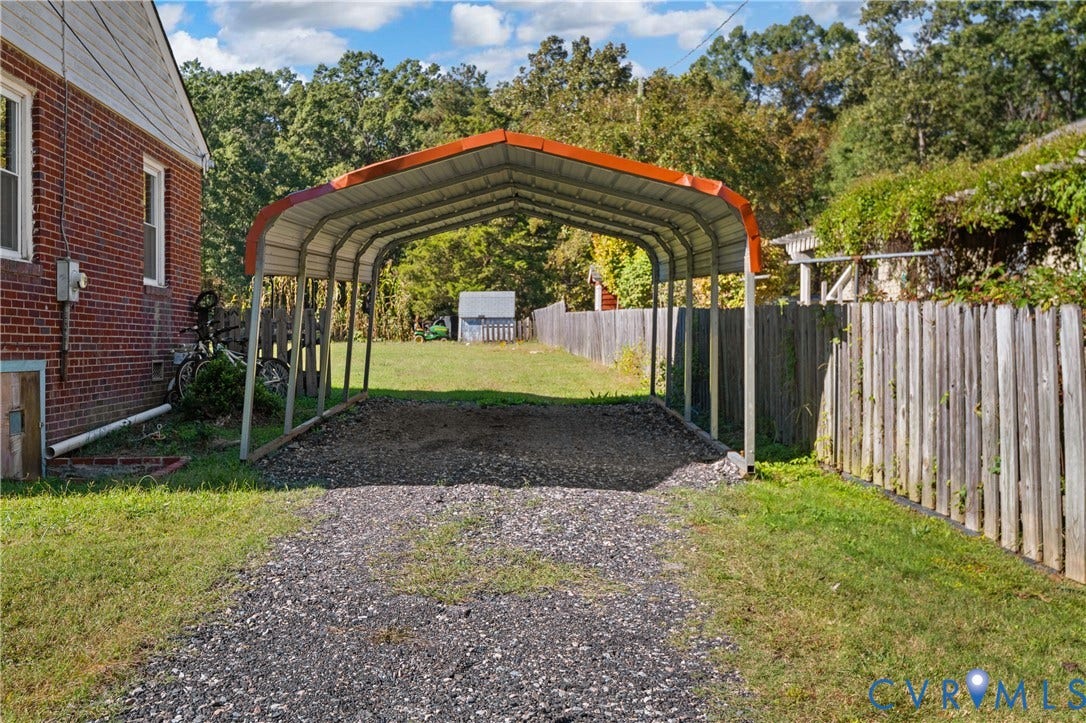 9834 N Wagstaff Circle, Mechanicsville, VA 23236 Detached metal carport featuring a gravel-surfaced parking area, red brick exterior walling, and fenced perimeter