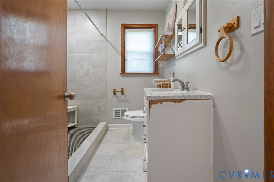9834 N Wagstaff Circle, Mechanicsville, VA 23236 Bathroom featuring large-format tile flooring, walk-in shower with light-toned wall tile, white vanity with stone-composite countertop, and wall-mounted medicine cabinet