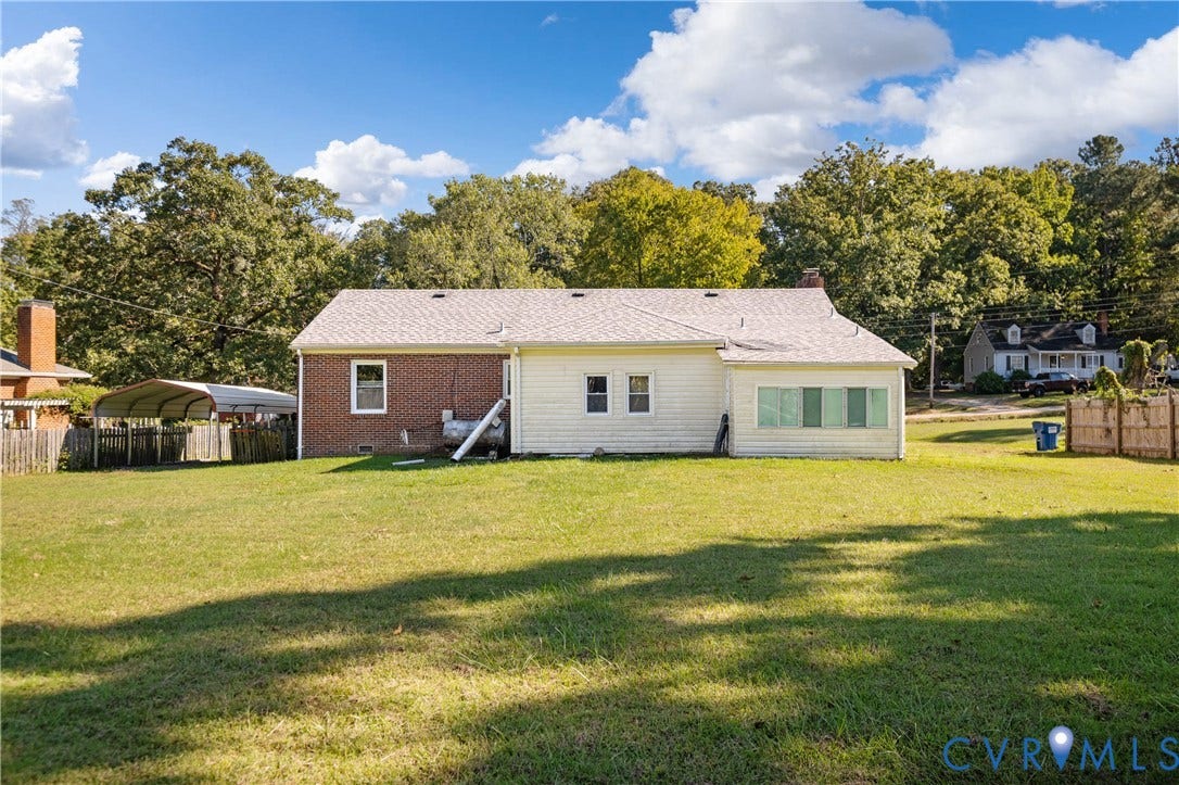 9834 N Wagstaff Circle, Mechanicsville, VA 23236 Expansive backyard featuring a large grass lawn, mature trees, brick and siding exterior, and a detached metal carport