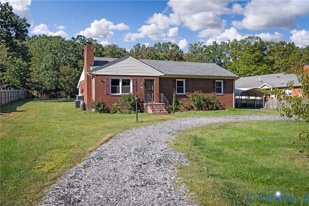9834 N Wagstaff Circle, Mechanicsville, VA 23236 Brick exterior residence featuring an attached exterior chimney, a gravel driveway, and a detached carport structure